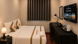 Ein Hotelzimmer mit Bett, Nachttisch, Lampe und Schreibtisch mit Stuhl.