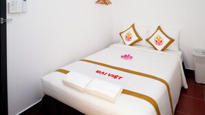 A hotel room with a bed, a towel, a wall-mounted heater, and a small trash bin. - The Rice Hotel & Tour - 195 De Tham (Ho Chi Minh City)