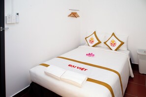 A hotel room with a bed, a towel, a wall-mounted heater, and a small trash bin. - The Rice Hotel & Tour - 195 De Tham (Ho Chi Minh City)