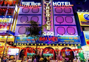 A brightly lit building with multiple signs, including "The Rice Hotel" and "Hai San Dai Viet Seafood." - The Rice Hotel & Tour - 195 De Tham (Ho Chi Minh City)