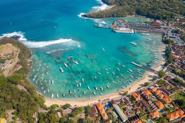 An aerial view of a coastal area with a marina, boats, and residential buildings.