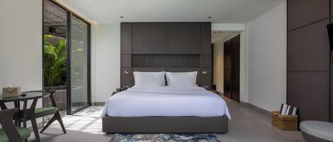 A modern bedroom with a large bed, a glass door leading to a balcony, a small table with chairs, and a large window.