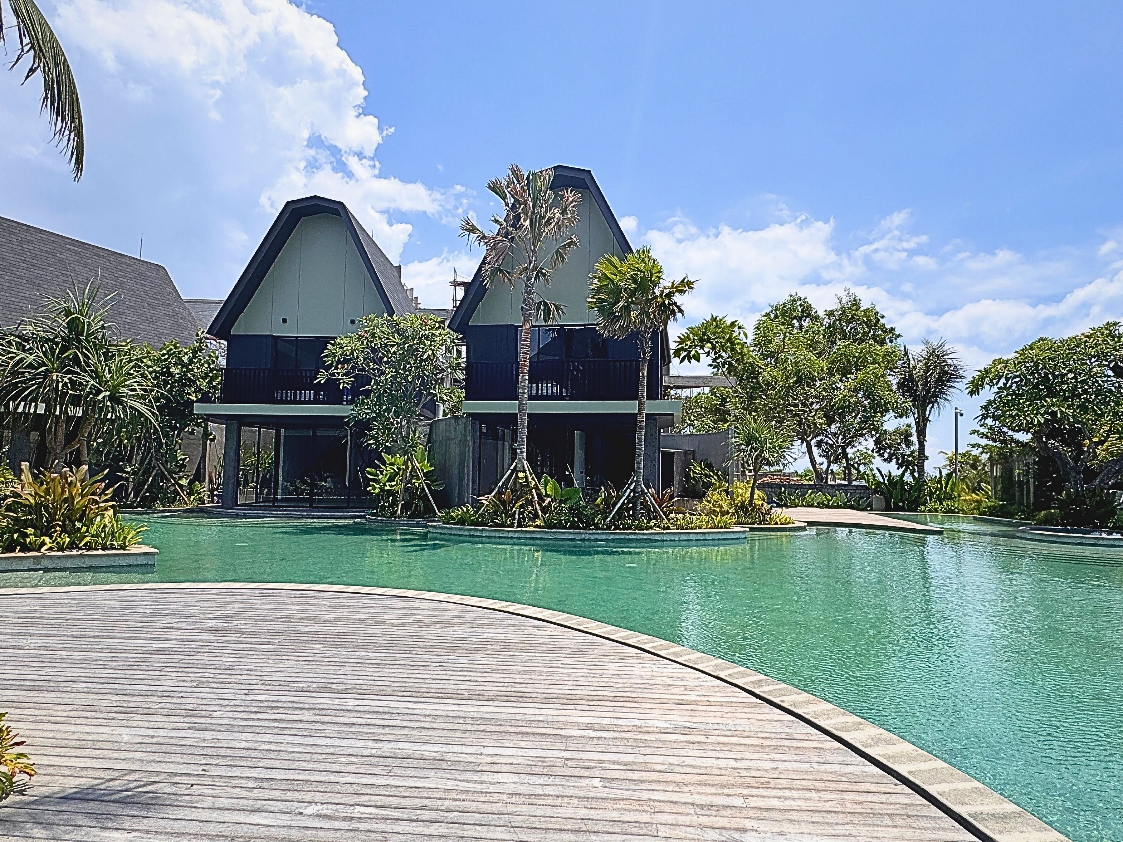 A resort with a swimming pool, two-story buildings, and tropical landscaping.