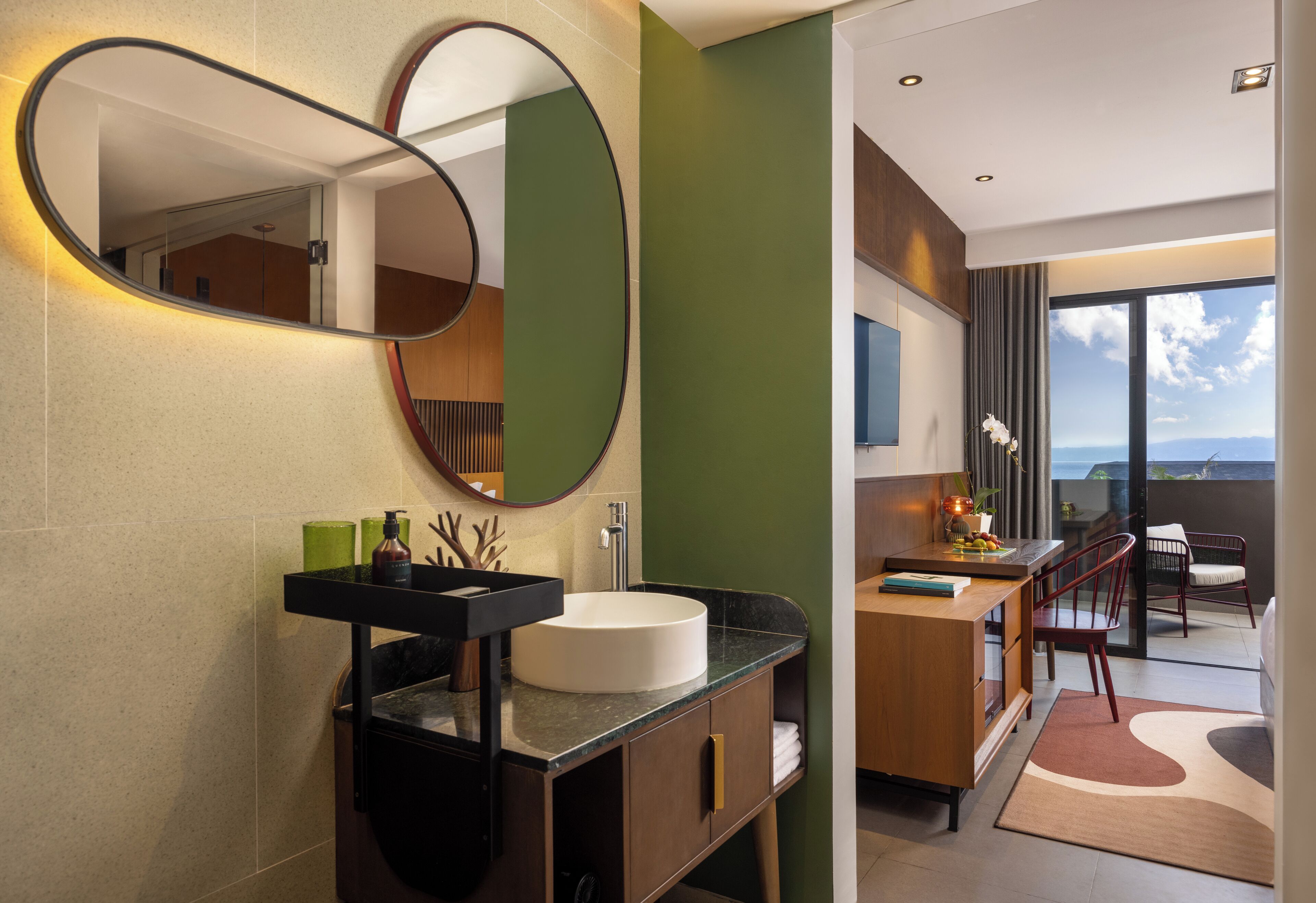 Une salle de bain moderne avec un miroir rond, un lavabo blanc et un meuble-lavabo en bois.