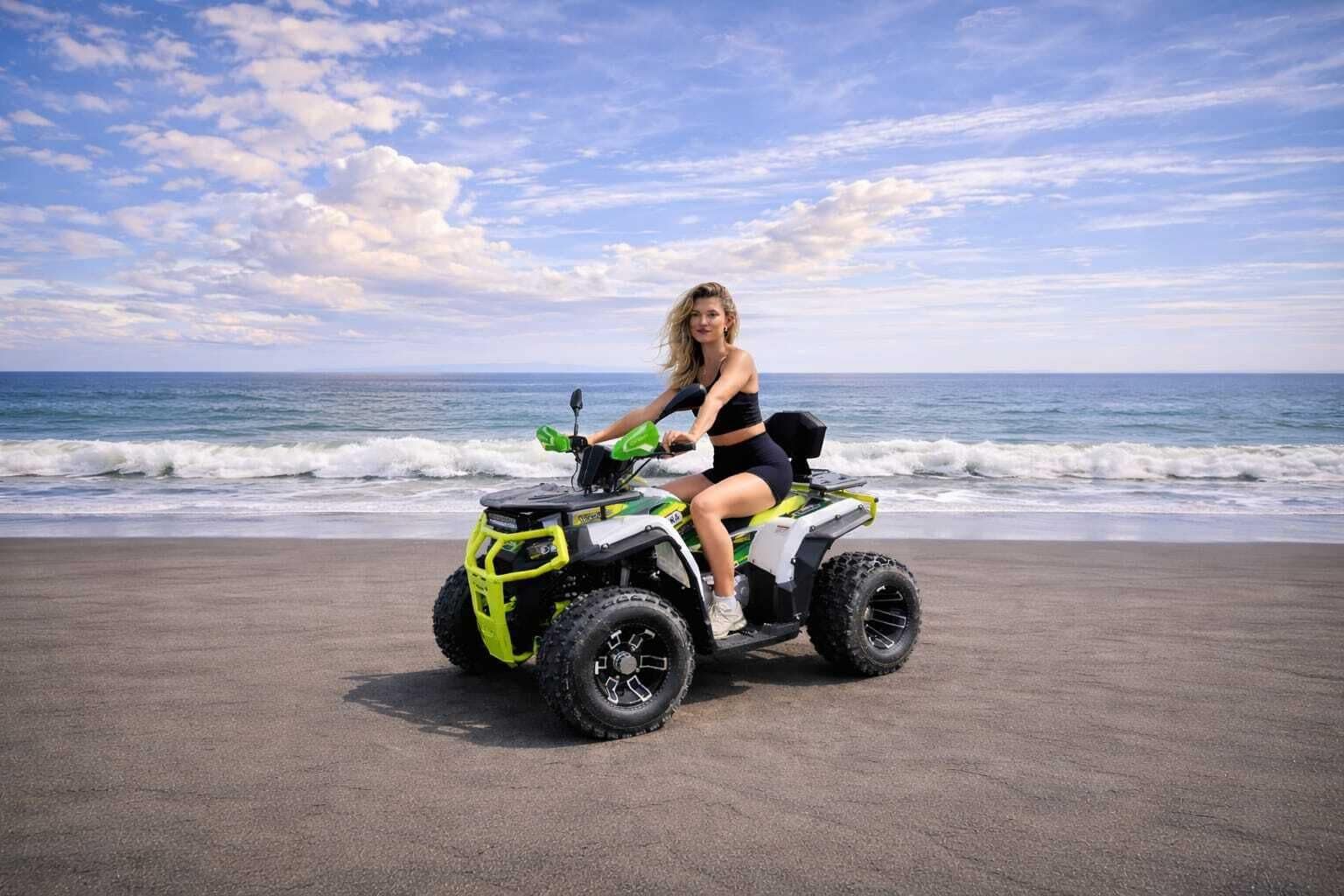 Une personne conduisant un quad jaune et noir sur une plage, avec l’océan en arrière-plan.