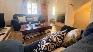 Ein Wohnzimmer mit einem dunkelblauen Sofa, einem Holztisch und einem Kamin.