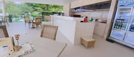 A clean, modern kitchen with a refrigerator, a dining area with chairs, and a small table with a menu.