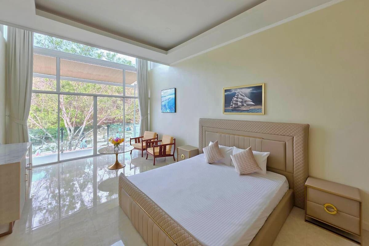 A modern hotel room with a large bed, a desk, and a view of the outdoors.