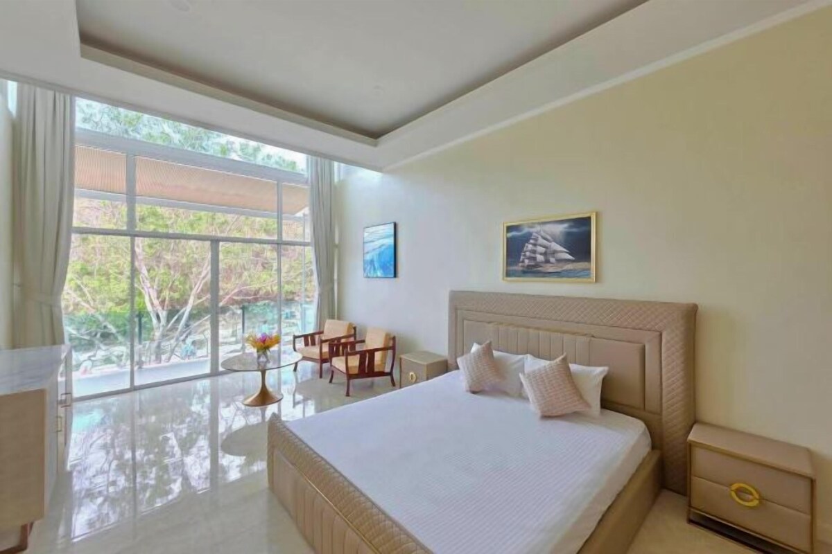 A spacious bedroom with a large bed, a desk, and a chair near a window.