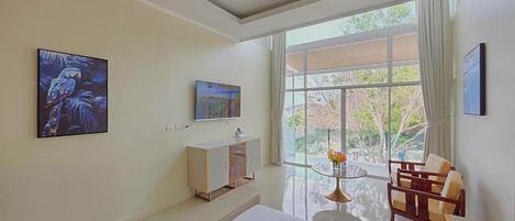 Camera d'albergo moderna con un letto grande, una scrivania, una sedia e una finestra vista alberi.