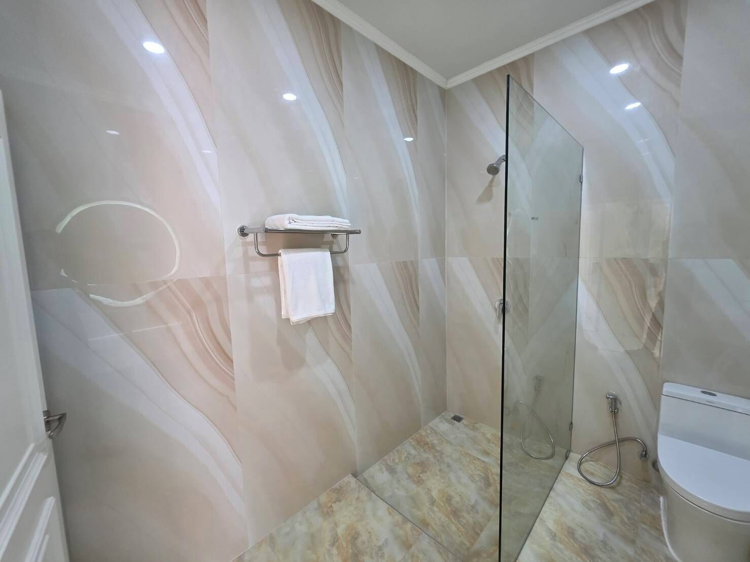 A modern bathroom with a glass shower enclosure, a toilet, and a towel rack.