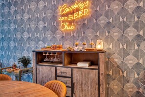 A room with a neon sign reading "Cowboy's and Beer Club," a wooden bar area with glasses and bottles, and a patterned wallpaper. - Rooftop deck & game room house • sleeps 12 • Nashville, TN (Nashville)
