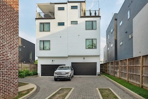 A modern multi-story residential building with a white exterior, two garages, and a brick wall on the left. - Summer rooftop deck, bbq, shuffleboard near Broadway (Nashville)