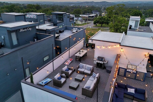 A rooftop patio with outdoor seating, a grill, and string lights. - Rooftop deck & game room house • sleeps 12 • Nashville, TN (Nashville)