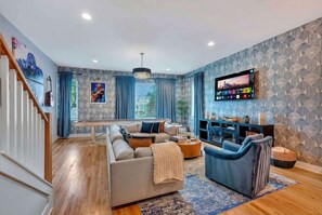 A living room with a sofa, armchairs, a coffee table, and a TV.
