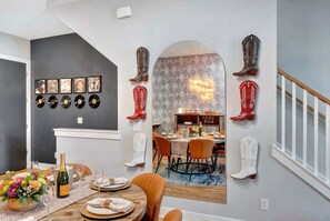 A dining area with a table set for four, a chandelier, and a wall decorated with cowboy boots and vinyl records.
