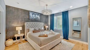 Ein Schlafzimmer mit einem großen Bett, Nachttischen, einer Chandelüster und einem Gemälde an der Wand.