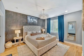 A bedroom with a large bed, bedside tables, a chandelier, and a painting on the wall. - Rooftop deck & game room house • sleeps 12 • Nashville, TN (Nashville)