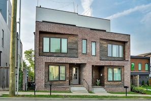 A modern two-story house with a brick facade, large windows, and a small front porch. - Rooftop deck & game room house • sleeps 12 • Nashville, TN (Nashville)