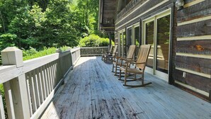 A wooden deck with rocking chairs, a wooden fence, and a view of trees. - Harrah`s Casino & Sequoyah National - 6 minutes (Whittier)