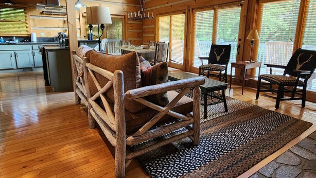 A rustic cabin interior with a wooden floor, a sofa, a dining table, and a kitchen area. - Harrah`s Casino & Sequoyah National - 6 minutes (Whittier)