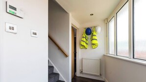 Un couloir avec un escalier, un radiateur et des casques de sécurité accrochés au mur.