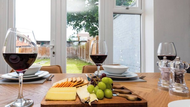 Une table à manger avec une planche à fromage, des raisins et des verres à vin.