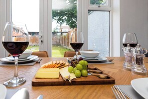 A dining table with a cheese board, grapes, and wine glasses. - Hazel House, 3BR, Crawley, Free Wifi, Parking , Gatwick (Crawley)