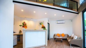 A modern living room with a central island, a sofa with orange cushions, and a coffee table. - Chiang Mai Midpoint Activitiy Hostel  (Chiang Mai)