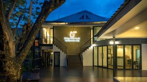 A modern building with a staircase leading to a second floor, a large illuminated sign, and a glass door entrance. - Chiang Mai Midpoint Activitiy Hostel  (Chiang Mai)