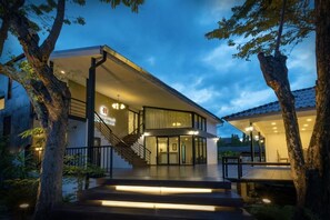 A modern building with a staircase leading to a covered entrance, surrounded by trees. - Chiang Mai Midpoint Activitiy Hostel  (Chiang Mai)