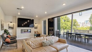 A spacious living room with a large sofa, a black leather chair, and a dining area with a table and chairs.