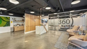 A modern office space with a reception area, a large number '360' sign, and a seating area with sofas.
