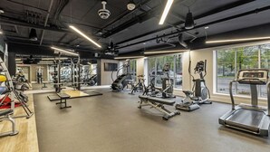 A gym with various exercise equipment, large windows, and a modern design.