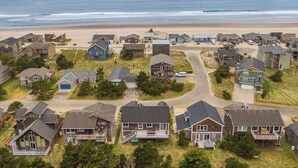Een woongebied met huizen, een strand en een rotsachtige landtong in de verte.