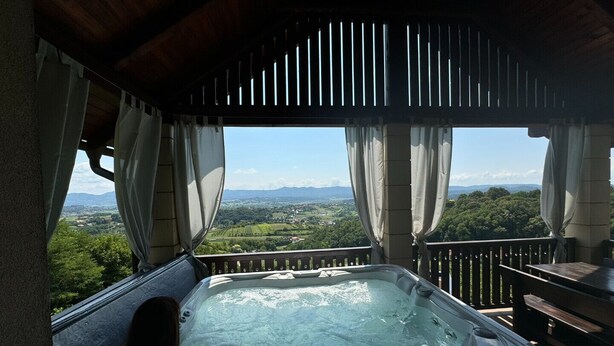 A hot tub on a balcony with a view of a landscape. - Relax With View – Panoramic Hideaway with Jacuzzi, Sauna & Absolute Calm (Remetinec)