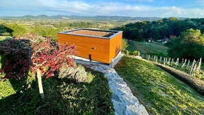 A modern building with a wooden facade, surrounded by lush greenery and a stone pathway. - Relax With View – Panoramic Hideaway with Jacuzzi, Sauna & Absolute Calm (Remetinec)
