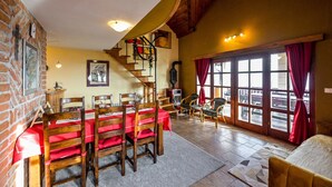 A dining area with a wooden table and chairs, a staircase, and a view through large windows. - Relax With View – Panoramic Hideaway with Jacuzzi, Sauna & Absolute Calm (Remetinec)