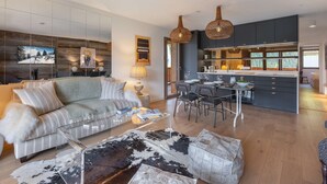 A modern living room with a sofa, coffee table, and a dining area with chairs and a table.