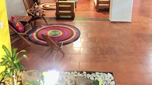 Un salon comprenant un ensemble de canapés, une table basse et un tapis à motifs. Il y a également un petit jardin avec des plantes et des rochers.