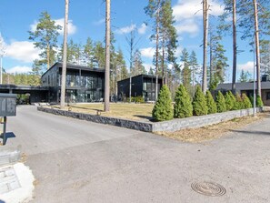 Moderni rakennus, jossa on asfaltoitu ajotie ja hyvin hoidettu nurmikko.