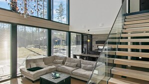 A modern living room with a sectional sofa, a coffee table, and a staircase.