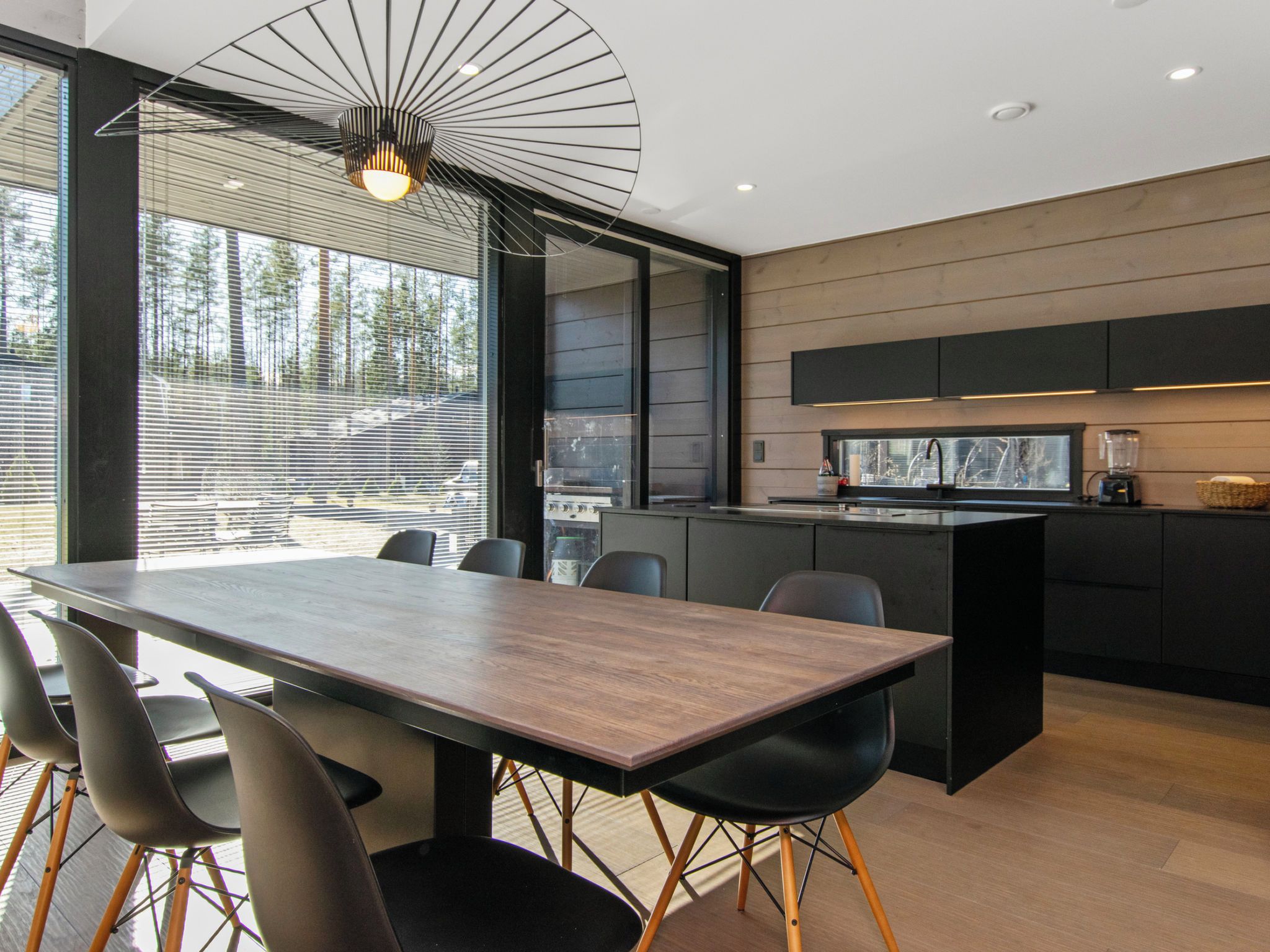 A modern kitchen with a central island, black cabinetry, and a built-in oven.