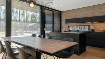A modern kitchen with a central island, black cabinetry, and a built-in oven.