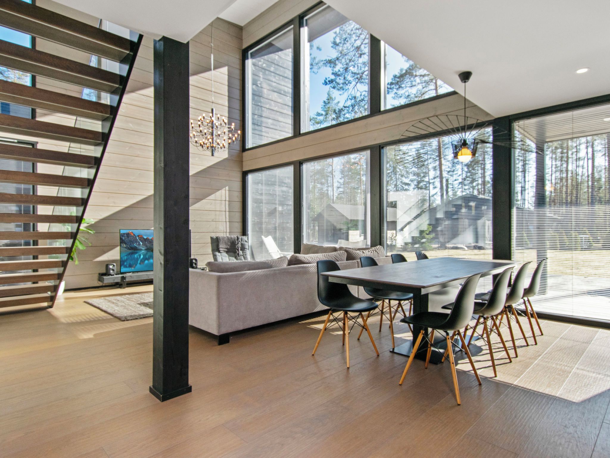 A modern interior with a staircase, a dining area, and large windows.