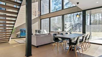 A modern interior with a staircase, a dining area, and large windows.