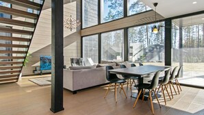 A modern interior with a staircase, a dining area, and large windows.