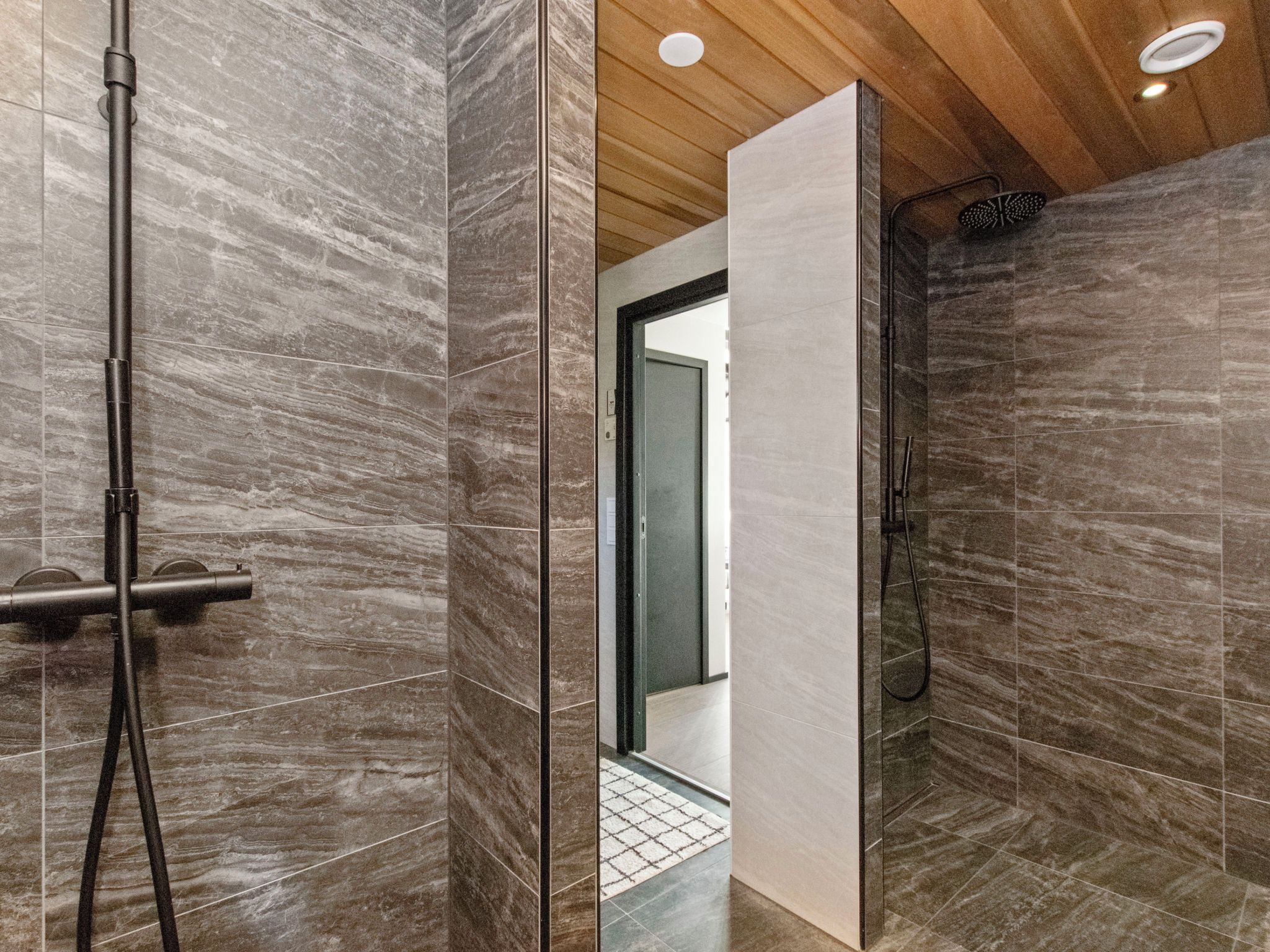Ein modernes Badezimmer mit Duschkabine aus Glas, Holzboden und gefliestem Boden.