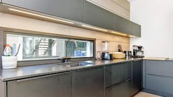 A modern kitchen with a large window, stainless steel appliances, and a wooden countertop.