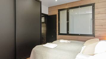 A bedroom with a bed, a wardrobe, and a window.